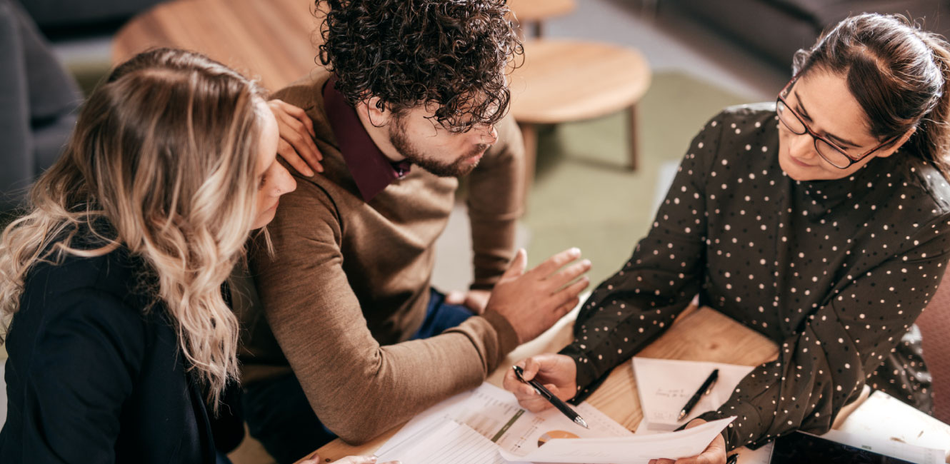 three people discussing paperwork